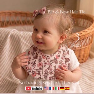 Puede incluir: Un bebé con un babero floral y una cinta para el pelo a juego. El babero y el lazo presentan un estampado floral rosa y blanco. La imagen también incluye el texto "Bib & Bow Hair Tie" y "3 Sizes".