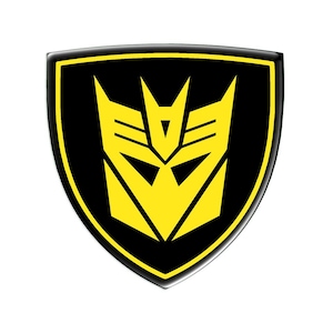 May include: A black and yellow shield-shaped emblem featuring a robot face design. The emblem has a black background with a yellow border and a yellow robot face in the centre. The design is a symbol from the Transformers franchise.