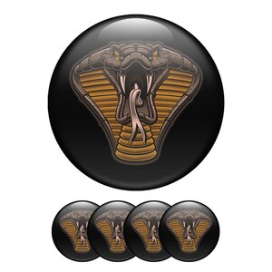 Op de afbeelding: Een set zwarte ronde knopen met een gedetailleerd cobra-ontwerp. De cobra heeft een bruine kop, een goudgele kap en een witte tong tegen een zwarte achtergrond. De set bevat één grote knoop en vier kleinere.