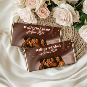 以下が含まれることがあります： 金色の縁取りが施された2つのチョコレートバー。テキスト「Waiting to Exhale Pajama Night」と、4人の女性が笑っている画像が特徴です。バーは織りのマットと白い布の上にあり、背景にはピンクのバラがあります。