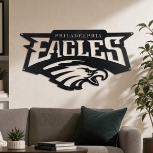 Op de afbeelding: Een zwart metalen wandbord met het logo en de tekst van de Philadelphia Eagles. Het ontwerp bevat het woord Philadelphia boven het woord Eagles in een vet, gestileerd lettertype, met een adelaarskop-afbeelding in het onderste gedeelte.