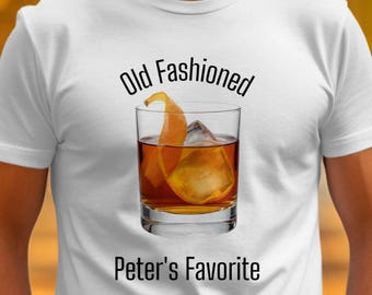 May include: White t-shirt with the text "Old Fashioned" above a graphic of a cocktail in a rocks glass with an orange peel and ice. Below the graphic is the text "Peter's Favorite".