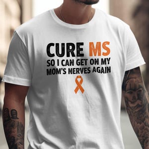 May include: A white short-sleeved t-shirt featuring the black text CURE MS SO I CAN GET ON MY MOM'S NERVES AGAIN, with the letters MS and a small awareness ribbon printed in orange.