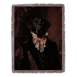 May include: Woven throw blanket featuring a portrait of a black Labrador Retriever dressed in formal attire. The dog wears a black suit with a ruffled shirt and a striped bow tie. The background has a dark red floral pattern.