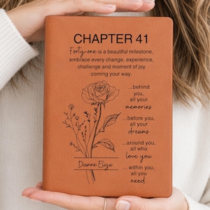 May include: A brown leather journal with the text "CHAPTER 41" and a floral design. The journal includes the text "Forty-one is a beautiful milestone, embrace every change..." and the name "Dianne Eliza".
