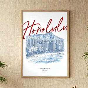 Puede incluir: Una impresión artística enmarcada con una ilustración azul y blanca de Honolulu, Hawái, con el horizonte de la ciudad, la playa y Diamond Head. La palabra "Honolulu" está escrita en rojo en la parte superior. El texto "State of Hawaii Est. 1907" está en la parte inferior.