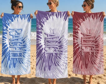 May include: Three rectangular beach towels featuring a radial tie-dye pattern in blue, purple, and red. Each towel displays a personalized name in white block lettering centered vertically: RACHEL on the blue, and ALICE on the purple and red.