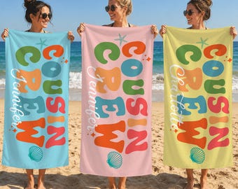 May include: Three rectangular beach towels in light blue, soft pink, and pale yellow. Each towel features the text "COUSIN CREW" in large, colorful, wavy letters, a personalized name in white script, and small starfish and seashell graphics.