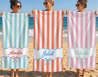 May include: Three rectangular beach towels featuring vertical stripes in turquoise, orange, and pink. Each towel has a white horizontal band at the bottom with a wavy border, a printed name in cursive script, and a small bow graphic below the name.