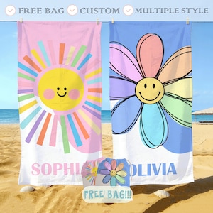 May include: Two beach towels with colorful designs. One is pink with a smiling sun, the other is blue with a smiling flower. The word "SOPHIA" is printed on the pink towel, and "OLIVIA" on the blue towel. A matching "FREE BAG" is included.