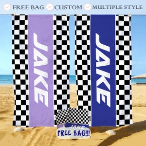 May include: Beach towels with a checkered pattern and the name "JAKE" in white. One towel is lavender, another is blue. A matching bag and a sign that says "FREE BAG!!!" are on the sand.