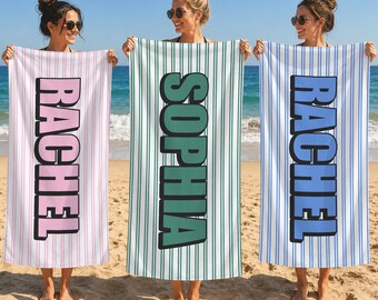 May include: Three rectangular beach towels featuring vertical pinstripes and large block lettering. The left towel is white with pink stripes and the name RACHEL. The center towel is white with green stripes and the name SOPHIA. The right towel is white with blue stripes and the name RACHEL.