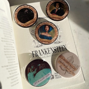 Peut inclure: Plusieurs badges ronds avec des illustrations et des citations du roman "Frankenstein" de Mary Shelley. Les épingles présentent des portraits, des citations et un motif de feuille. Le titre du livre et le nom de l'auteur sont visibles.