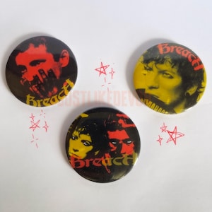 Può includere: Tre bottoni rotondi neri e gialli con ritratti rossi e gialli e la scritta "Breach". I bottoni hanno un'estetica punk rock. Scarabocchi di stelle rosse sono sparsi intorno ai bottoni.