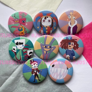 Pode incluir: Uma coleção de sete botões redondos coloridos com personagens de desenhos animados extravagantes. Cada botão tem um design único, incluindo um bobo da corte, um rei, um coelho e uma boneca. Os botões são colocados sobre um fundo de papel rosa, verde e branco.