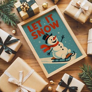 May include: A framed print featuring the words "LET IT SNOW" and a snowman illustration. The print is surrounded by wrapped gifts with ribbons and bows, pine branches, and gold baubles, creating a festive holiday scene.