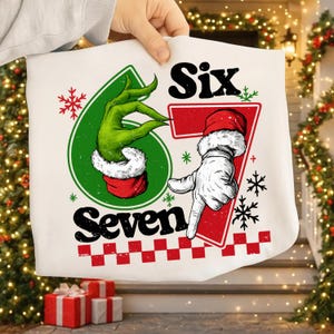 May include: White Christmas-themed pillowcase with the numbers six and seven. The number six is represented by a green hand in a red and white Santa hat. The number seven is represented by a white gloved hand in a Santa hat.