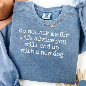 Può includere: Una felpa blu a girocollo con finitura lavata vintage. La parte anteriore presenta un testo ricamato in bianco che recita: do not ask me for life advice you will end up with a new dog. Il capo include un'etichetta sul collo del marchio Comfort Colors.