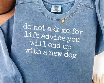 May include: A blue crewneck sweatshirt with a vintage-wash finish. The front features white embroidered text that reads: do not ask me for life advice you will end up with a new dog. The garment includes a Comfort Colors brand neck label.