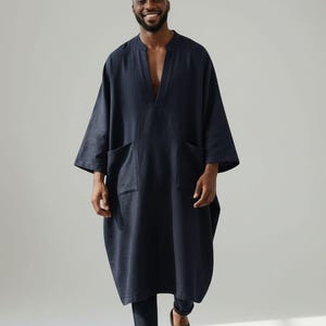 Op de afbeelding: Een donkerblauwe tuniek met lange mouwen, een diepe V-hals en twee grote opgestikte zakken aan de voorzijde, gecombineerd met een bijpassende donkerblauwe slim-fit broek en zwarte slippers. De tekst Shahig Fabric Fusion staat onderaan.