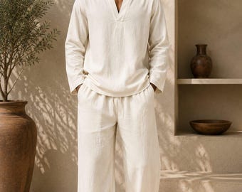 Può includere: Una camicia a maniche lunghe color crema con scollo a V e pantaloni larghi abbinati con vita elastica e coulisse. L'outfit è completato da sandali neri e occhiali da sole. Il testo Shahig Fabric Fusion è visibile nell'angolo in basso.
