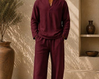 Può includere: Un completo color bordeaux scuro composto da una camicia a maniche lunghe con scollo a V e pantaloni ampi coordinati con elastico in vita e coulisse. Il tessuto presenta una finitura testurizzata e il testo Shahig Fabric Fusion è stampato in basso.