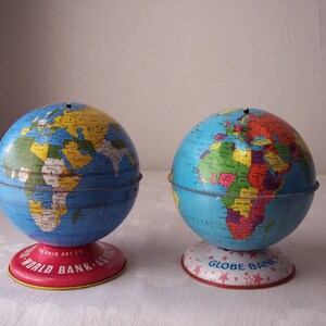 May include: Two vintage globe shaped metal piggy banks. One is blue and red with the text "World Bank - As - Is" and the other is blue and red with the text "Globe Bank".
