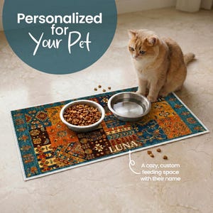 May include: A personalized pet feeding mat with the name "LUNA" printed on it. The mat features a colorful, patterned design with a teal border. Two stainless steel bowls sit on the mat, one filled with dry food and the other with water. A cat is sitting next to the mat.