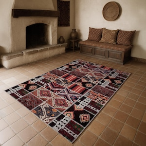 Peut inclure: Un grand tapis rectangulaire en patchwork avec un motif géométrique dans les tons de rouge, noir, orange et crème. Le tapis est posé sur un sol carrelé dans une pièce avec une cheminée et des bancs.