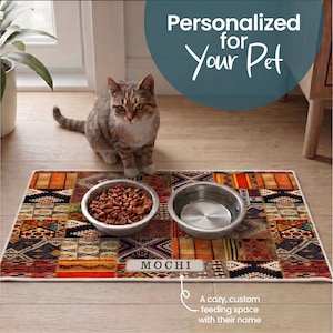 May include: A cat sits beside a personalized pet feeding mat with two stainless steel bowls. The mat features a colourful patchwork design and the name "MOCHI". Text reads "Personalized for Your Pet."