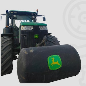 Puede incluir: Un tractor John Deere verde y negro con neumáticos grandes. El tractor tiene un accesorio frontal negro con el logotipo verde y amarillo de John Deere. El tractor está diseñado para uso agrícola.