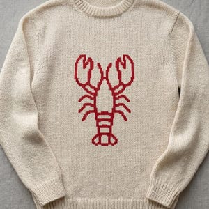 Puede incluir: Suéter color crema con diseño de langosta roja. El suéter de cuello redondo presenta un gráfico de langosta tejido en el centro. El suéter de manga larga está hecho de un material suave y texturizado, perfecto para uso casual.
