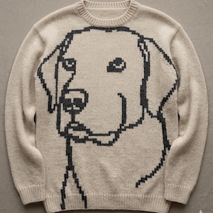 May include: Beige knit sweater featuring a pixelated dog design in dark gray. The crew neck sweater has long sleeves and a ribbed collar, cuffs, and hem. The dog's face is prominently displayed on the front of the sweater.