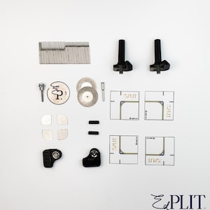 Könnte beinhalten: Eine Auswahl an schwarzen und silbernen Werkzeugen und Komponenten, darunter kleine Kreissägeblätter, schwarze Griffe und quadratische Schablonen mit dem Text "EPLIT". Die Werkzeuge sind auf einer weißen Oberfläche angeordnet.