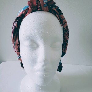 May include: A knotted headband with a floral print in shades of pink, blue, and brown.