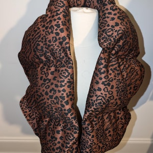 May include: A brown and black leopard print infinity scarf. The scarf is made of a soft, comfortable fabric and is perfect for keeping warm in the winter.