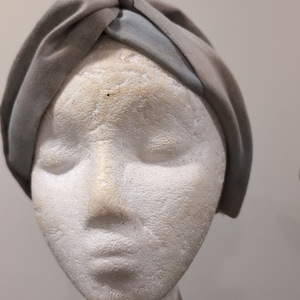 May include: A white mannequin head wearing a gray and blue turban-style head wrap.