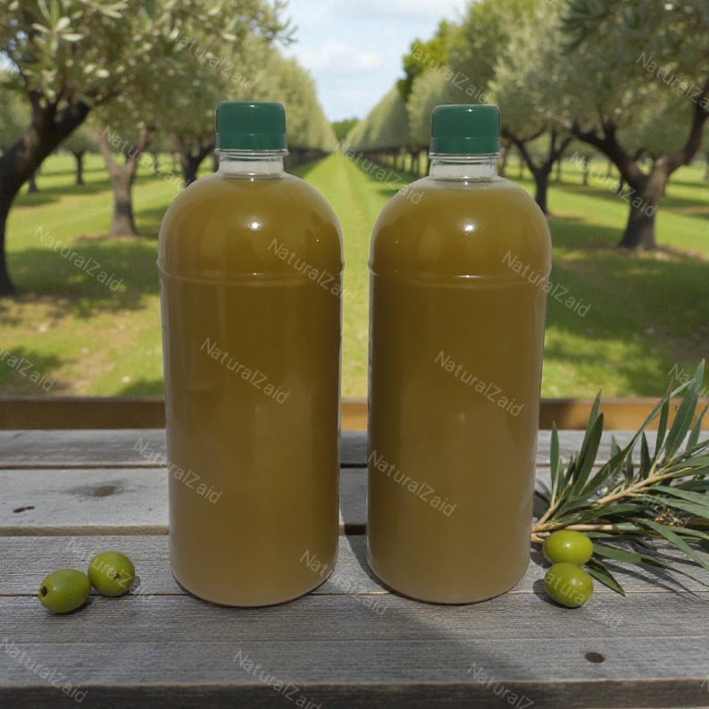 Puede incluir: Dos botellas de pl&aacute;stico transparente llenas de aceite de oliva, cada una con una tapa verde. Est&aacute;n sobre una superficie de madera, con aceitunas verdes y ramas de olivo. El fondo muestra un olivar. Las botellas tienen el texto "NaturalZaid".