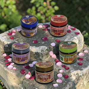 May include: Five round jars of Savon Noir soap with colored lids, including blue, red, purple, green, and brown. Each jar features a label with text and imagery corresponding to its scent, such as lavender, eucalyptus, and argan oil.