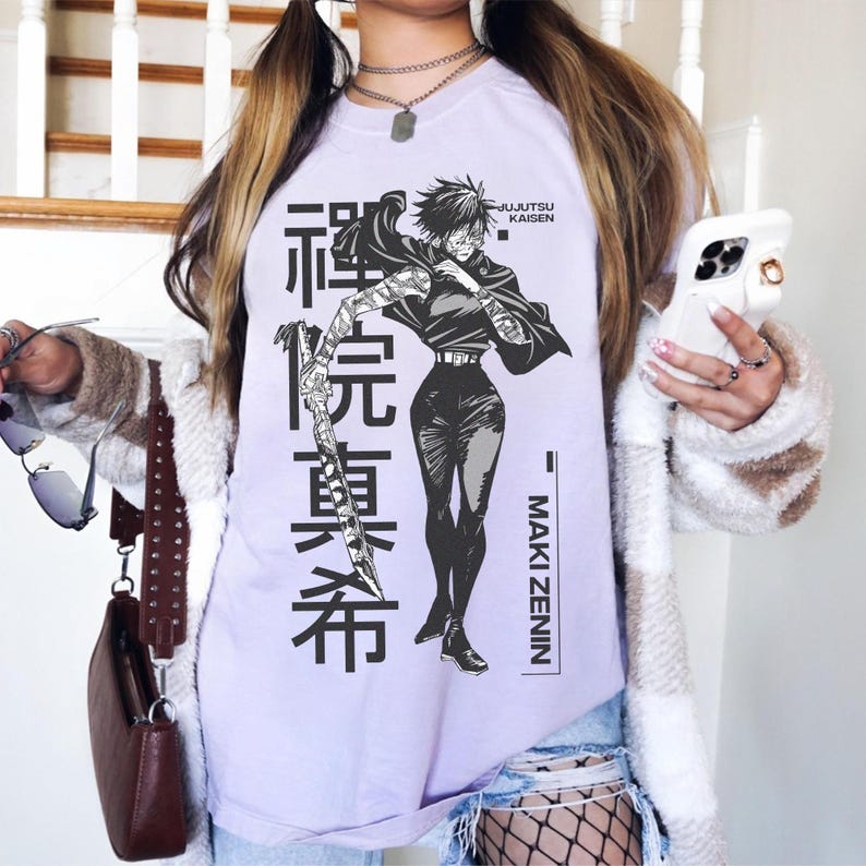 May include: A light purple t-shirt featuring a black and white graphic of a character from Jujutsu Kaisen, with Japanese text and the name "Maki Zenin". The design includes a character holding a sword.