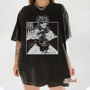 May include: Black t-shirt featuring a black and white graphic of a character from an anime series. The graphic is inside a white rectangle with Japanese text. The shirt has short sleeves and a relaxed fit.