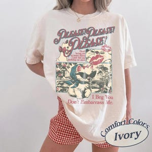 May include: Cream-coloured Comfort Colors t-shirt with a retro graphic of cartoon cats and the text "PLEASE! PLEASE! PLEASE!". The graphic includes the phrases "Don't bring me to tears" and "I Beg You Don't Embarrass Me."