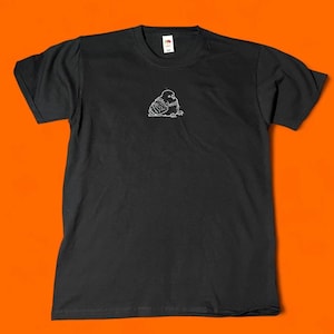 May include: Black t-shirt with a small, white, hand-drawn illustration of a bird on the front. The bird is depicted in a simple, minimalist style. The shirt is made of a soft material and has short sleeves.