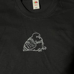 May include: Black t-shirt with a white graphic of a stylized owl. The shirt has a crew neck and short sleeves. The brand logo is visible at the top of the shirt.
