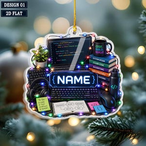 May include: A flat, hanging ornament featuring a computer setup with a laptop displaying code, a keyboard, headphones, a stack of books labeled with programming topics, a water bottle, a notepad, and a central sign with the text NAME.