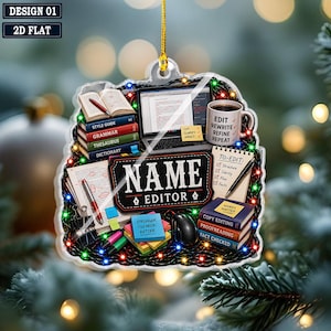 May include: A flat, hanging ornament featuring a desk scene with books, a laptop, a mug labeled 'EDIT REWRITE REFINE REPEAT', and a notepad. The center text reads 'NAME EDITOR'. The design is surrounded by colorful string lights on a dark background.