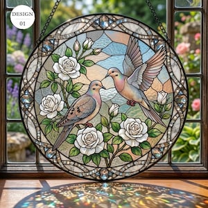 May include: A circular stained glass suncatcher featuring two doves among white roses and green leaves. One dove is perched while the other is in flight. The border is decorated with clear faceted glass accents. The text DESIGN 01 is visible.