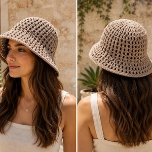 May include: A beige crochet bucket hat featuring an open-weave grid pattern. The hat has a rounded crown and a downward-sloping brim that provides coverage around the head. The construction consists of interconnected yarn loops in a neutral tan color.