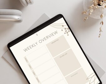 Op de afbeelding: Een digitale weekplanner op een tablet met de woorden "WEEKLY OVERVIEW", "PRIORITIES", "TO-DO LIST" en "REMINDER". De tablet ligt op een wit oppervlak met een koptelefoon en een vaas met gedroogde bloemen. De tekst "Download Now" staat bovenaan.