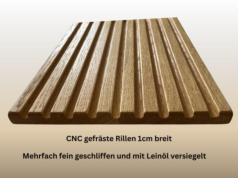 May include: A rectangular wooden board with parallel grooves, likely for a kitchen or decorative purpose. The wood has a warm, natural tone. The text on the board reads "CNC milled grooves 1cm wide" and "Multiple finely ground and sealed with linseed oil."
